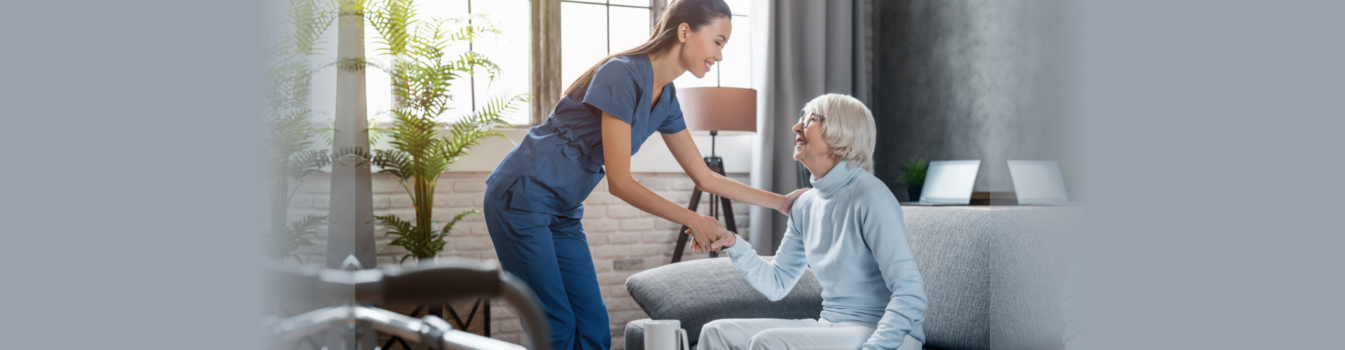 Happy female professional caregiver taking care of elderly woman at home